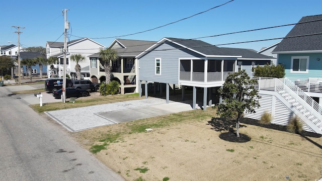 view of front facade with a sunroom, a residential view, driveway, stairway, and a carport