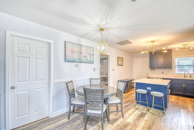 dining room featuring crown molding, a chandelier, visible vents, and light wood-style floors