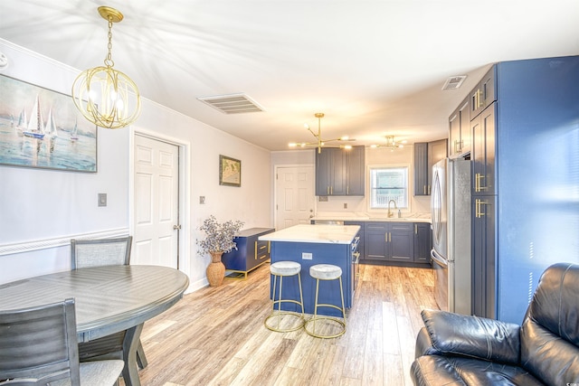 kitchen with a chandelier, freestanding refrigerator, visible vents, and a sink