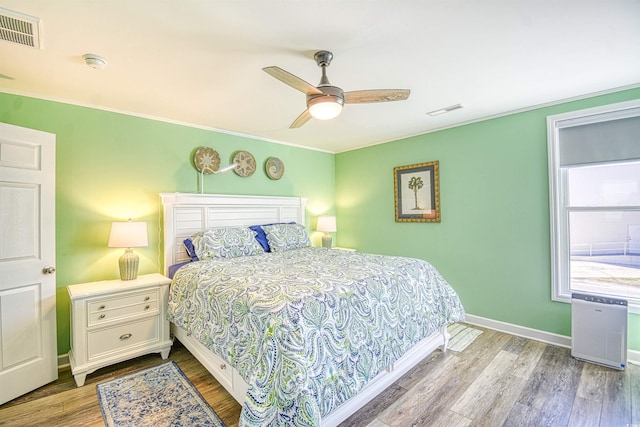 bedroom featuring a ceiling fan, baseboards, visible vents, and wood finished floors