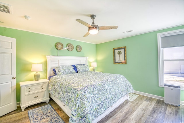 bedroom featuring crown molding, baseboards, visible vents, and wood finished floors