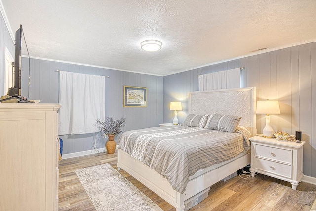 bedroom with a textured ceiling, ornamental molding, and wood finished floors