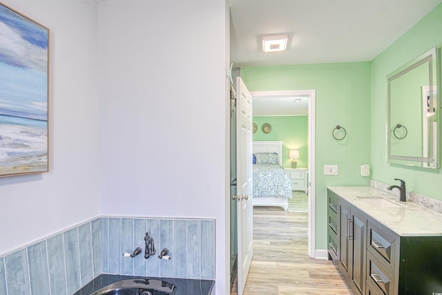 ensuite bathroom with vanity, a bathtub, ensuite bath, and wood finished floors