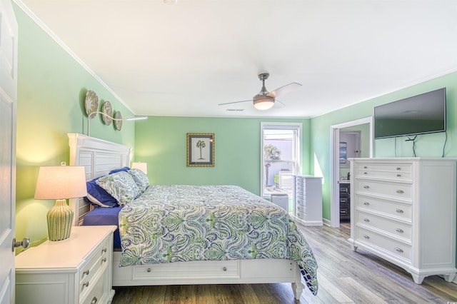 bedroom featuring a ceiling fan, wood finished floors, visible vents, and crown molding