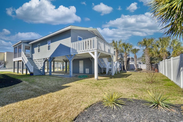 back of property with a deck, a fenced backyard, stairs, a lawn, and a carport