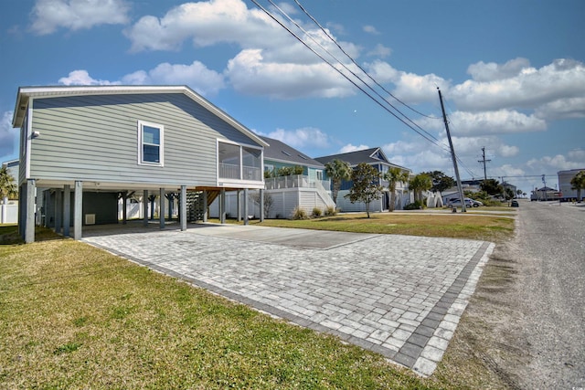 exterior space with stairs, a carport, a front lawn, and decorative driveway