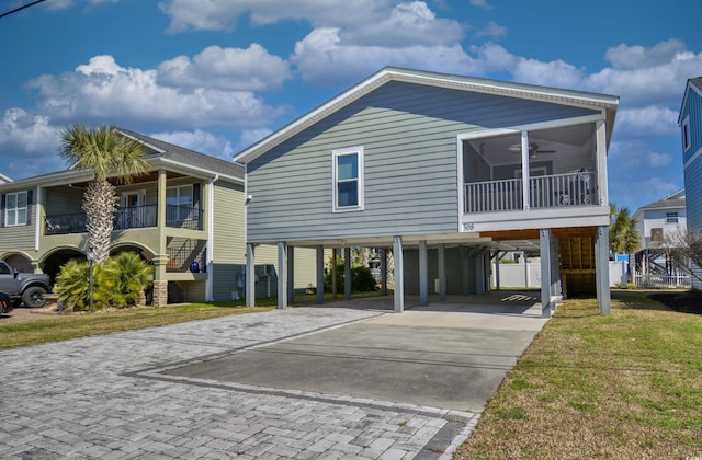 beach home featuring ceiling fan, driveway, a front lawn, and a carport