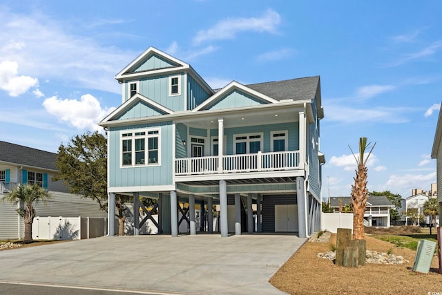 coastal home featuring driveway, a shingled roof, a balcony, a carport, and board and batten siding