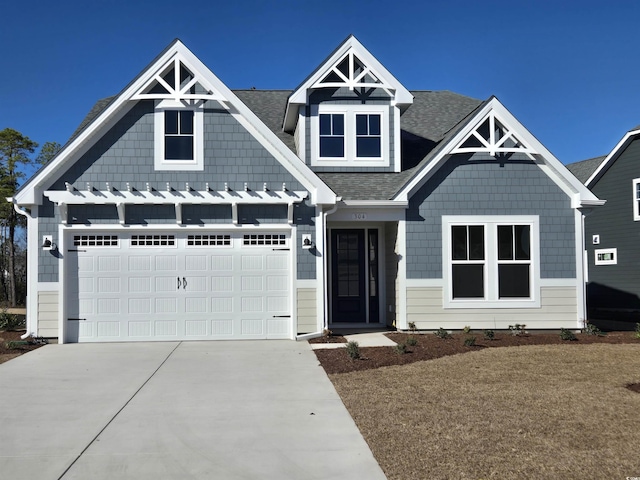 view of front facade featuring a shingled roof and concrete driveway