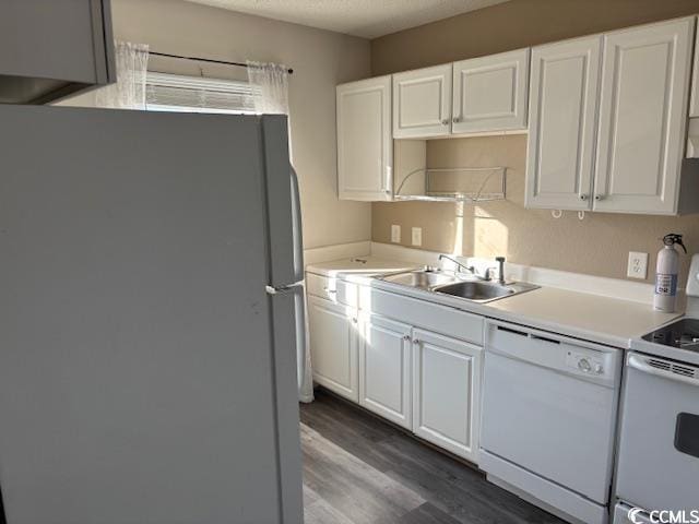 kitchen with sink, white appliances, white cabinets, and dark wood-type flooring