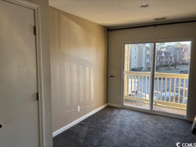 empty room with dark colored carpet and a textured ceiling