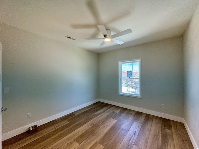 unfurnished room featuring baseboards, a ceiling fan, dark wood-style floors, and visible vents