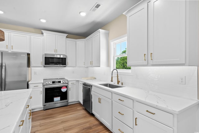 713 9th Ave S, North Myrtle Beach, SC 29582 - kitchen featuring appliances with stainless steel finishes, white cabinets, tasteful backsplash, recessed lighting, and light wood-style flooring