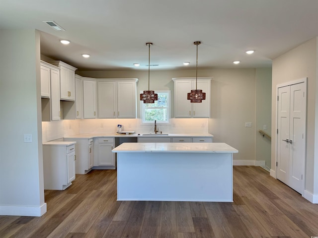 kitchen with dark wood-style flooring, visible vents, a center island, tasteful backsplash, and a sink