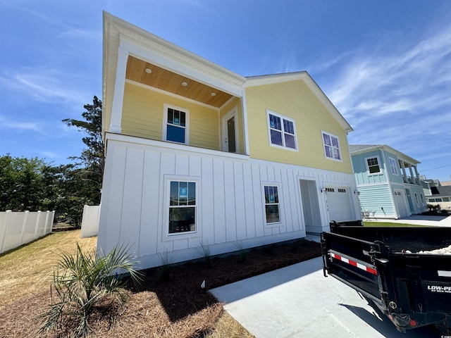 view of front of home with board and batten siding, fence, and a garage