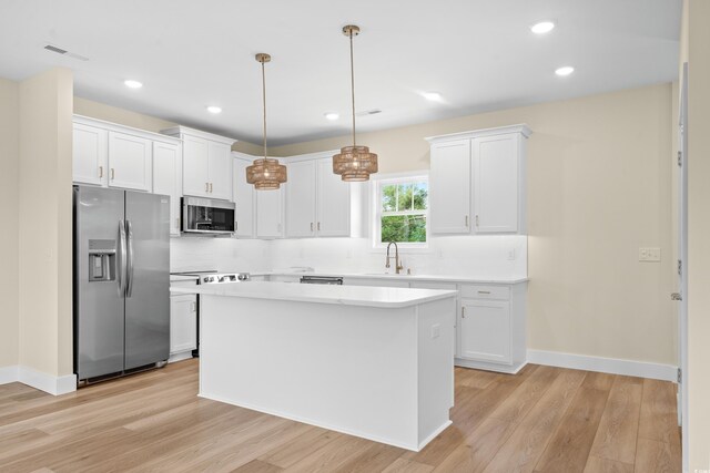 713 9th Ave S, North Myrtle Beach, SC 29582 - kitchen with stainless steel appliances, light wood finished floors, white cabinetry, light countertops, and a center island