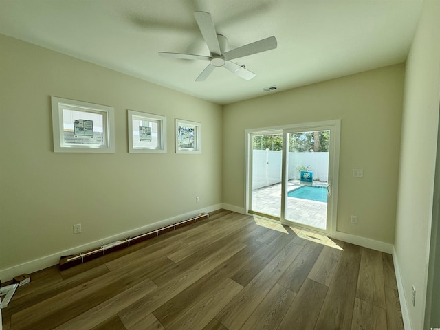 spare room featuring visible vents, baseboards, ceiling fan, and wood finished floors