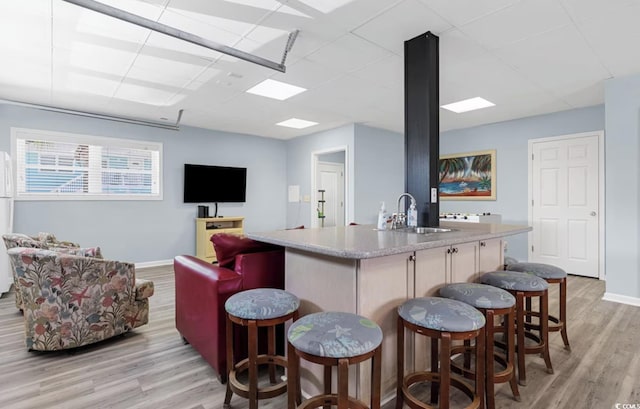 bar with white fridge, light hardwood / wood-style flooring, and sink