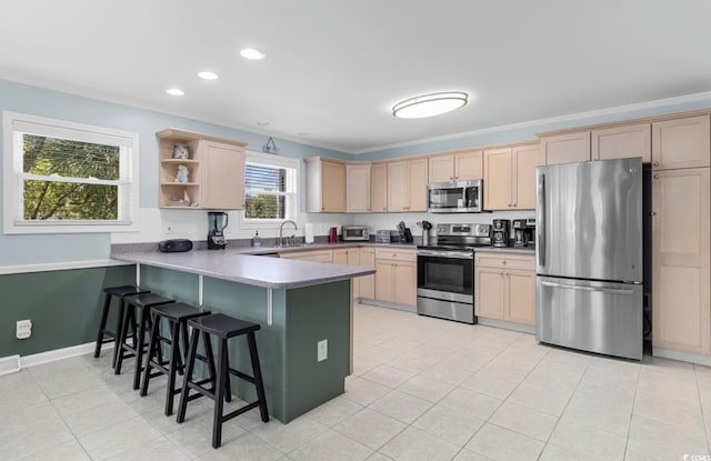 kitchen with stainless steel appliances, a breakfast bar, ornamental molding, sink, and kitchen peninsula