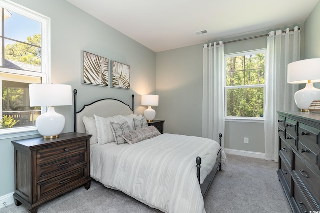bedroom with visible vents, light carpet, and baseboards