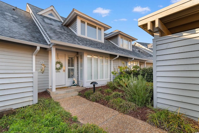 view of exterior entry with a shingled roof