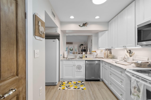 kitchen with light countertops, visible vents, appliances with stainless steel finishes, white cabinetry, and a sink