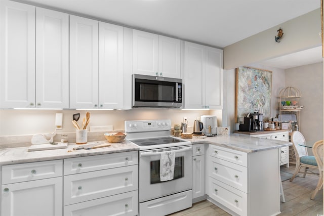 kitchen featuring light stone countertops, white electric range oven, stainless steel microwave, and white cabinets