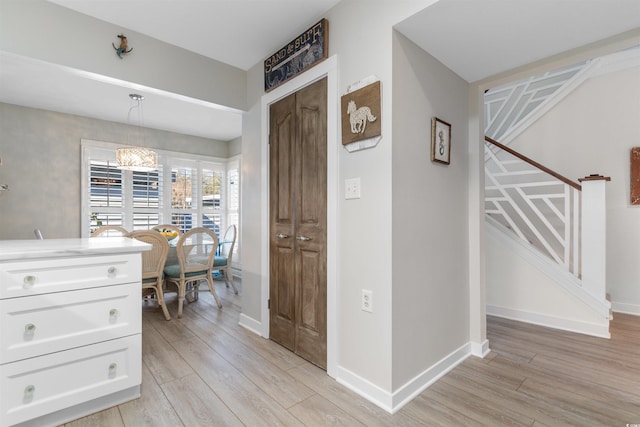 interior space with light wood-type flooring, stairway, and baseboards