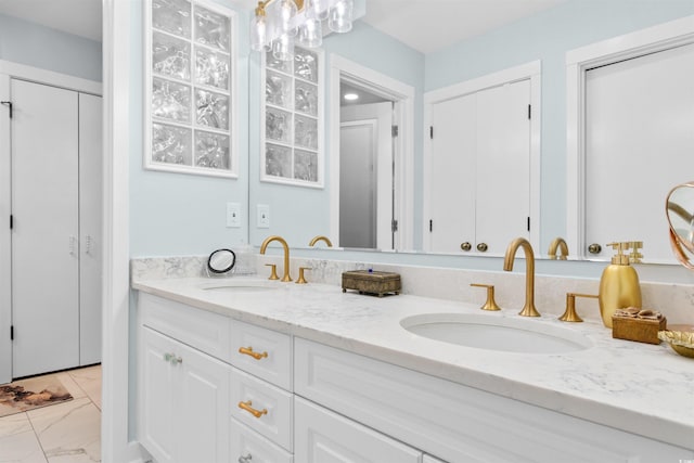 bathroom with marble finish floor, a sink, and double vanity