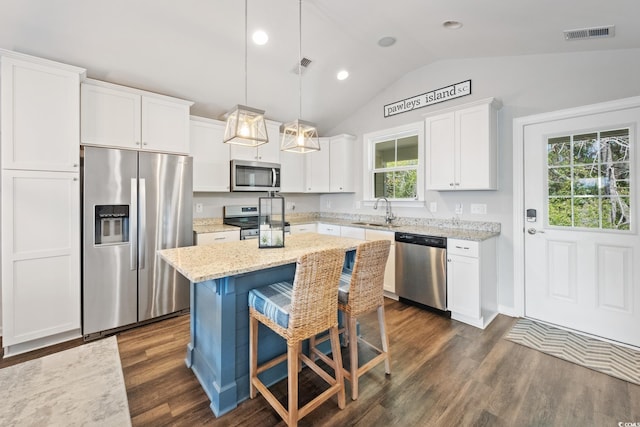 kitchen featuring a sink, white cabinets, appliances with stainless steel finishes, a center island, and pendant lighting