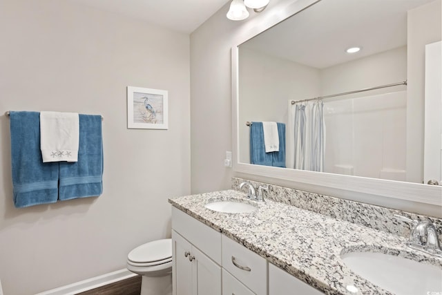 bathroom featuring double vanity, a sink, toilet, and baseboards