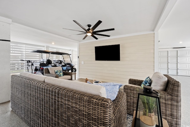 living area featuring ceiling fan, speckled floor, and wooden walls