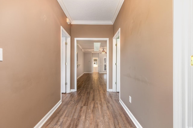 hallway featuring baseboards, ornamental molding, and wood finished floors