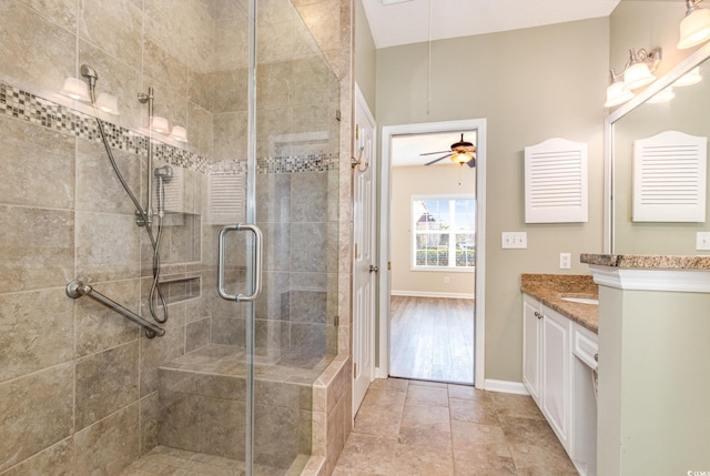 bathroom with baseboards, vanity, a shower stall, and tile patterned floors