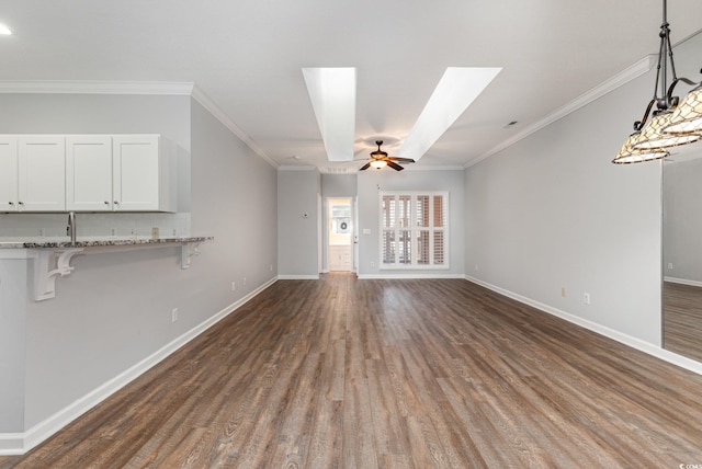 unfurnished living room featuring a ceiling fan, baseboards, ornamental molding, and dark wood-type flooring