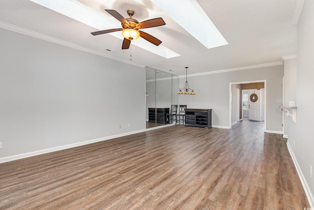 unfurnished living room featuring a skylight, ornamental molding, a ceiling fan, wood finished floors, and baseboards