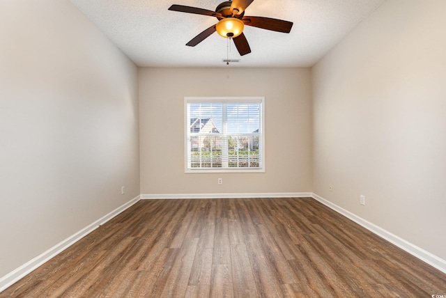 spare room featuring a textured ceiling, ceiling fan, dark wood-type flooring, and baseboards