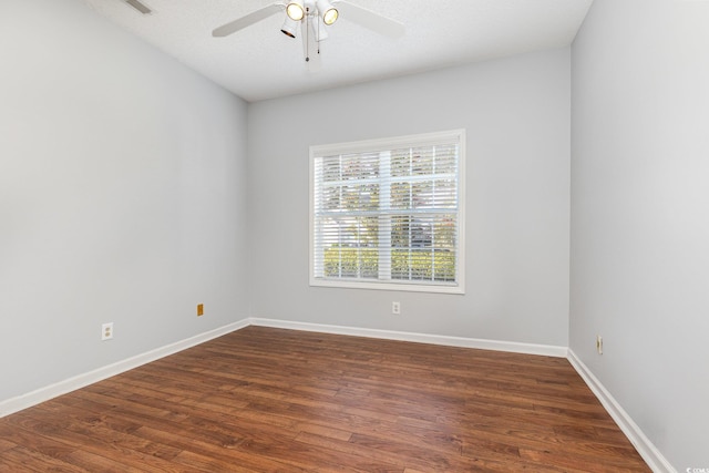 spare room featuring ceiling fan, baseboards, and dark wood-style flooring