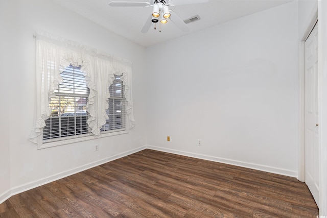 empty room with dark wood-style flooring, visible vents, ceiling fan, and baseboards