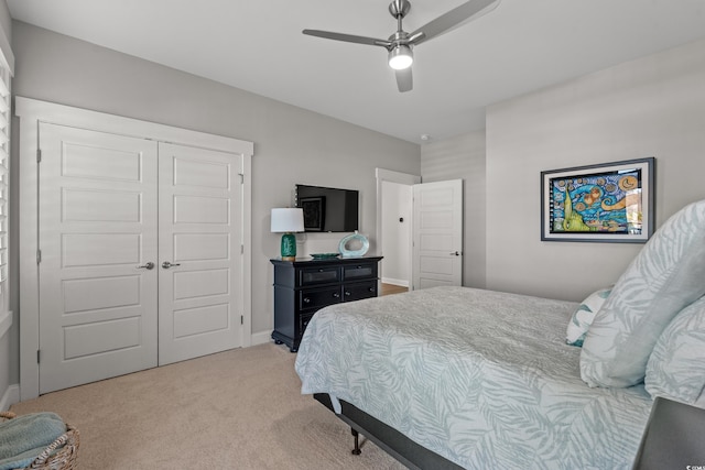 bedroom with light carpet, a ceiling fan, baseboards, and a closet