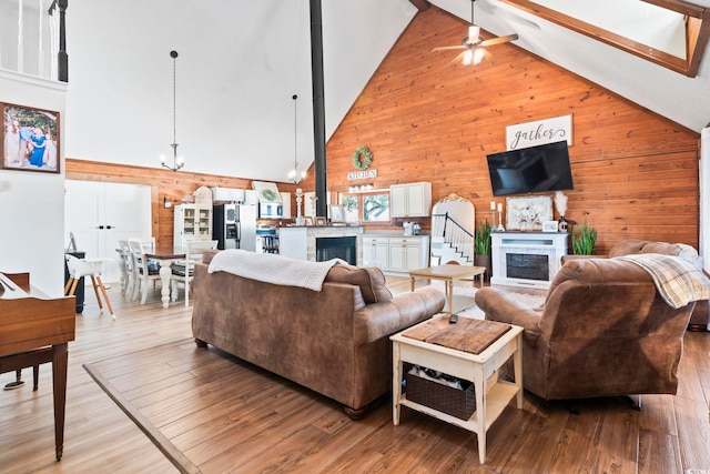 living room with light hardwood / wood-style floors, high vaulted ceiling, wooden walls, and beam ceiling