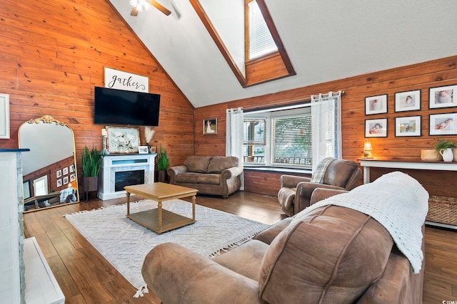 living room featuring ceiling fan, high vaulted ceiling, wood-type flooring, and wood walls