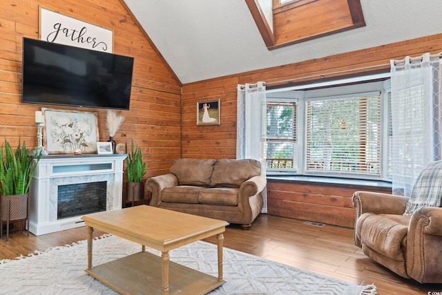 living room featuring a high end fireplace, light hardwood / wood-style floors, lofted ceiling, and wooden walls