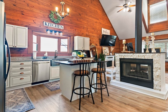 kitchen with white cabinetry, a stone fireplace, sink, appliances with stainless steel finishes, and a breakfast bar area