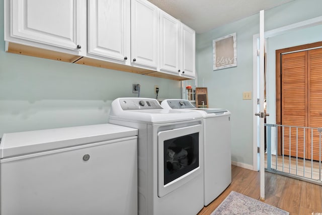 clothes washing area featuring washer and dryer, cabinets, and light hardwood / wood-style floors