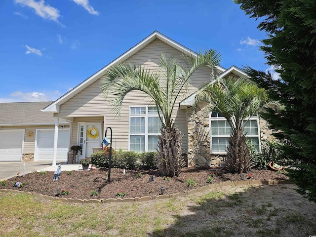 view of front facade featuring stone siding, an attached garage, and driveway