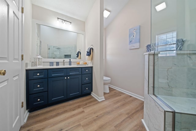 full bath featuring toilet, wood finished floors, vanity, baseboards, and tiled shower