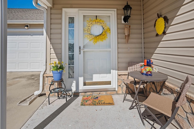 entrance to property with a garage and roof with shingles