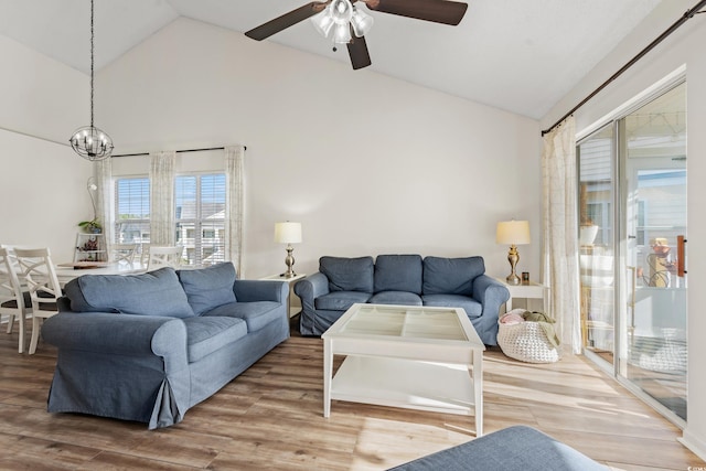 living area with high vaulted ceiling, wood finished floors, and ceiling fan with notable chandelier