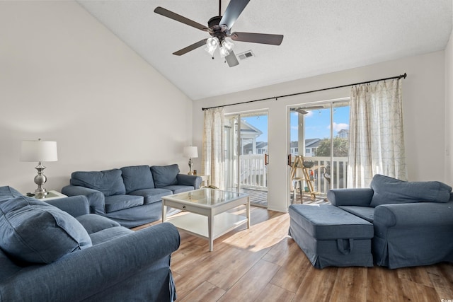 living area with visible vents, lofted ceiling, ceiling fan, a textured ceiling, and light wood-type flooring